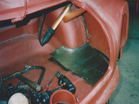 Laswerk in een carrosserie, met een lasbrander en een hamer.