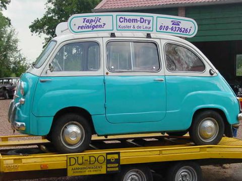 Een turquoise met witte Fiat 600 Multipla op een aanhanger.