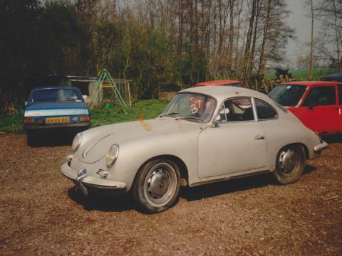 Een lichtgrijze Porsche 356 op een grindpad.