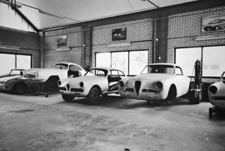 Een zwart-witfoto van de werkplaats, met drie Alfa Romeo-carrosserieën op een rij.