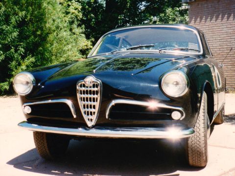 Een zwarte Alfa Romeo coupé met chromen bumper, van voren.