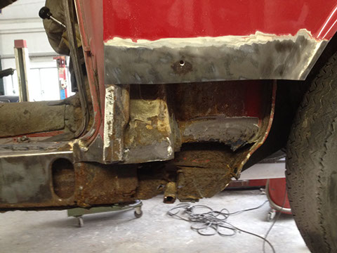 De onderkant van de Giulia Sprint GT met roest bij de dorpel en de wielkast, rechtsboven blank plaatwerk.